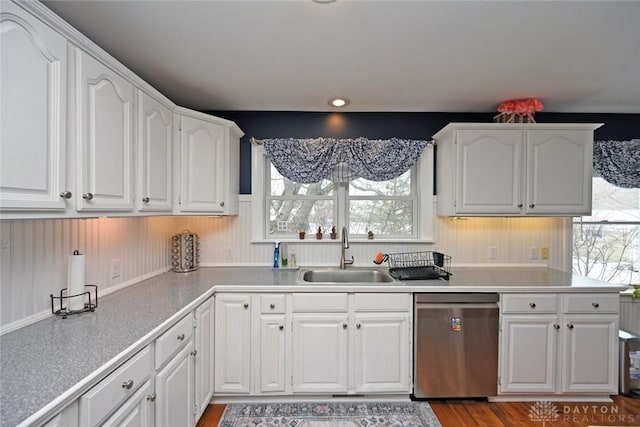 kitchen featuring stainless steel dishwasher, a sink, and white cabinetry