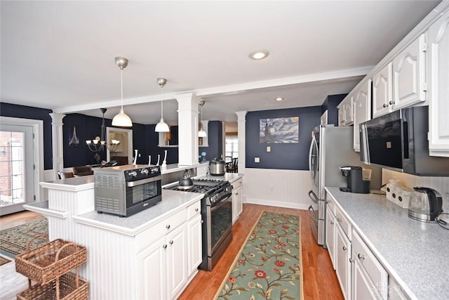 kitchen featuring light countertops, stainless steel range with gas stovetop, decorative light fixtures, and white cabinetry