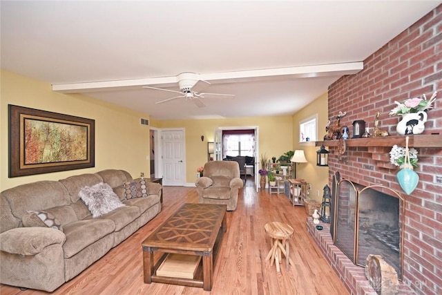 living area featuring beamed ceiling, visible vents, and light wood-style floors