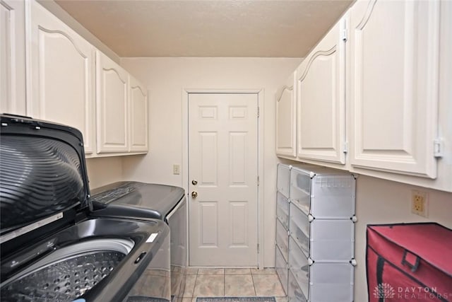 laundry room with cabinet space, light tile patterned floors, and washer and dryer