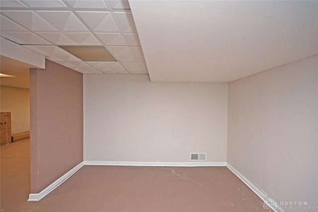 spare room with a drop ceiling, visible vents, and baseboards