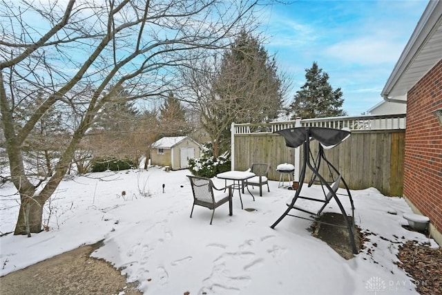 yard layered in snow featuring a shed, an outdoor structure, and fence