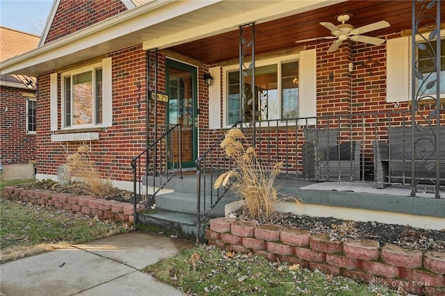 view of exterior entry with covered porch, ceiling fan, and brick siding