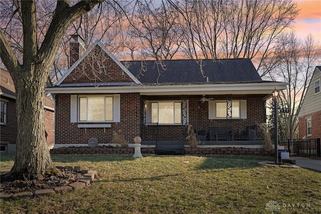 view of front of house featuring a porch, a front lawn, and brick siding