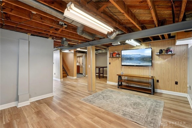 finished basement featuring wooden walls, stairway, wood finished floors, and baseboards