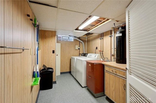 washroom featuring light floors, wooden walls, and separate washer and dryer