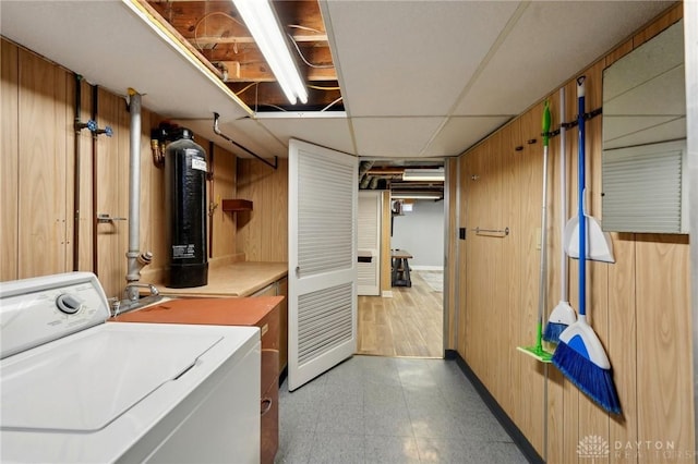 laundry room with light floors, washer / dryer, and wooden walls