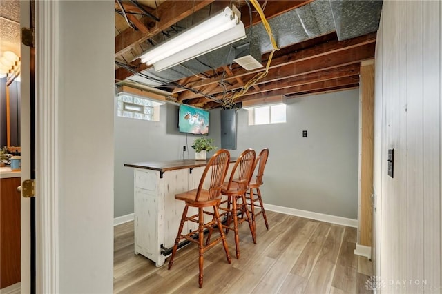 bar featuring a bar, wood finished floors, electric panel, and baseboards