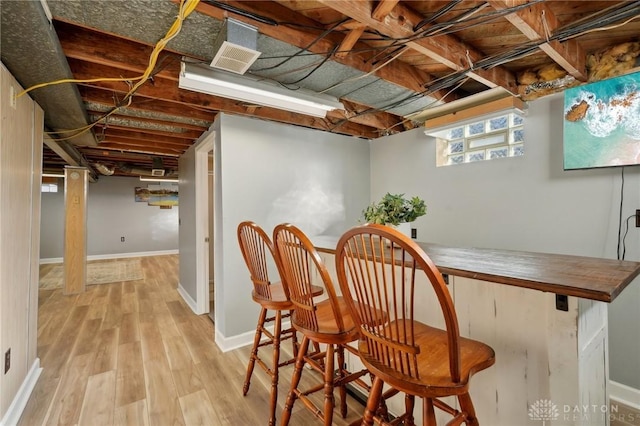 interior space featuring baseboards, light wood finished floors, and a bar