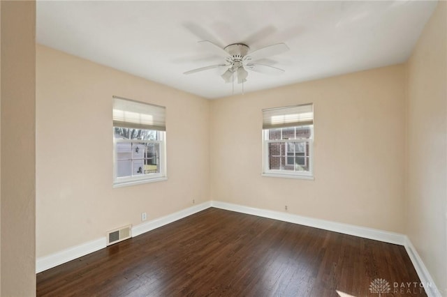 empty room featuring dark wood finished floors, visible vents, plenty of natural light, and baseboards