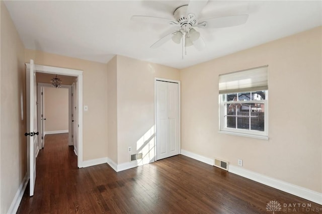 unfurnished bedroom with visible vents, baseboards, a ceiling fan, dark wood finished floors, and a closet