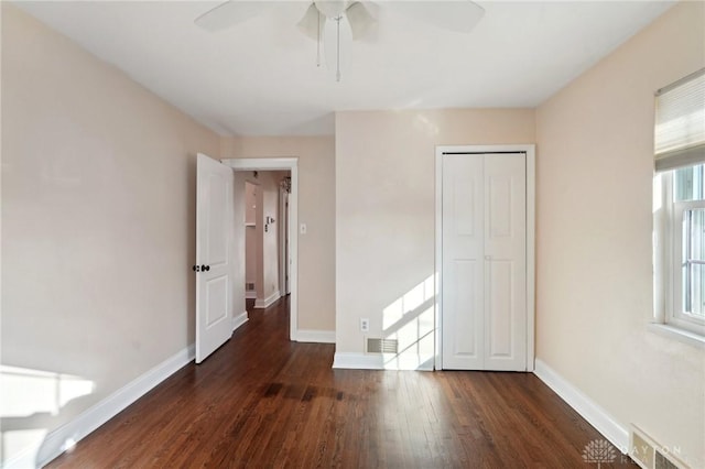 unfurnished bedroom with dark wood-type flooring, a closet, visible vents, and baseboards