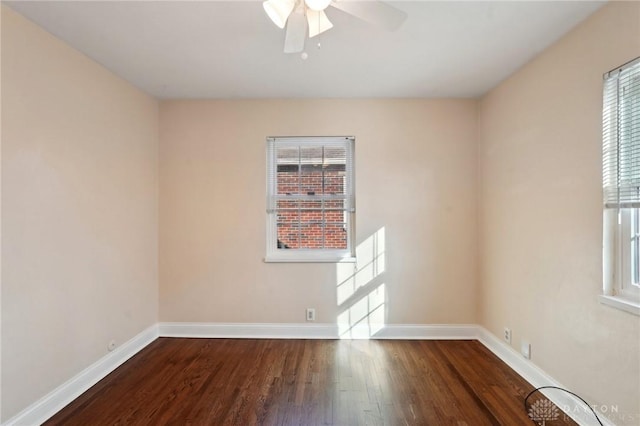 spare room featuring dark wood-type flooring, a ceiling fan, and baseboards