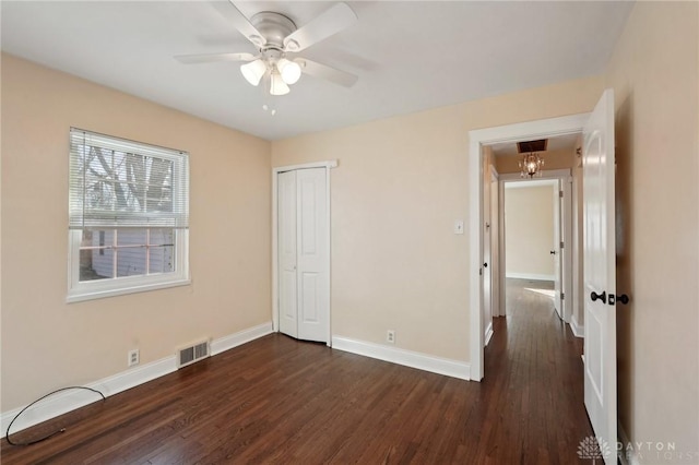 unfurnished bedroom featuring baseboards, visible vents, and dark wood-style flooring