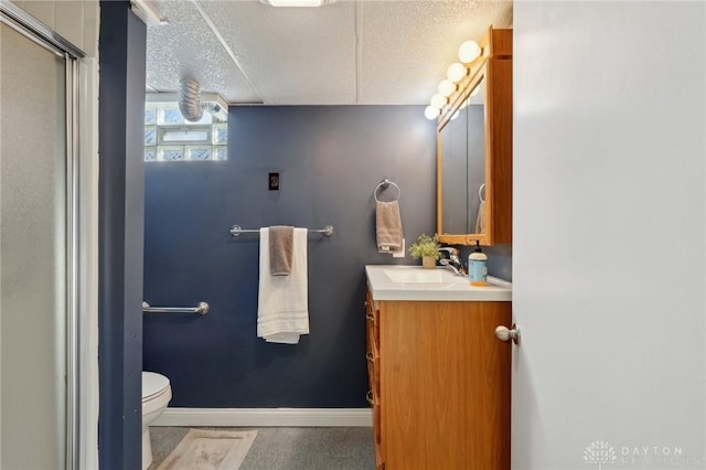 bathroom featuring a stall shower, baseboards, toilet, a textured ceiling, and vanity