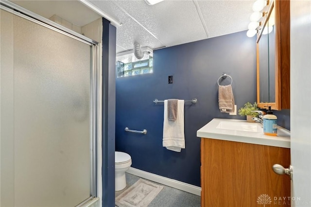 bathroom featuring toilet, a shower stall, baseboards, and vanity