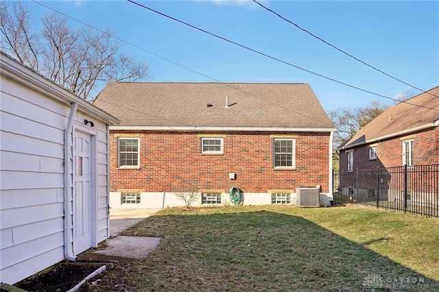 back of house with roof with shingles, brick siding, a yard, fence, and cooling unit