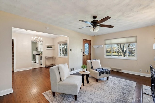 living area featuring dark wood-type flooring, plenty of natural light, visible vents, and baseboards