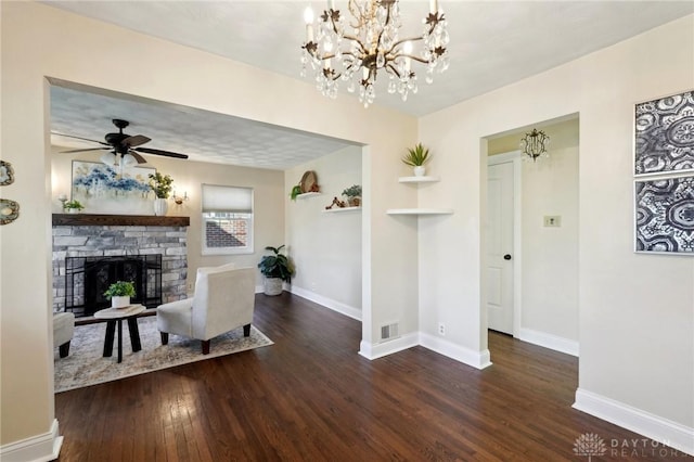 living room with baseboards, visible vents, dark wood-style floors, a fireplace, and ceiling fan with notable chandelier