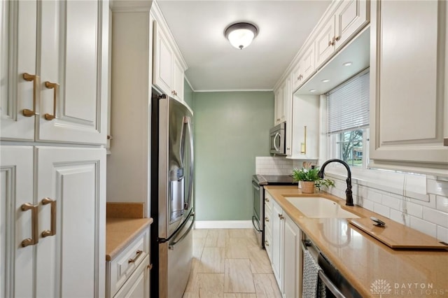 kitchen featuring stainless steel appliances, a sink, white cabinetry, light countertops, and tasteful backsplash