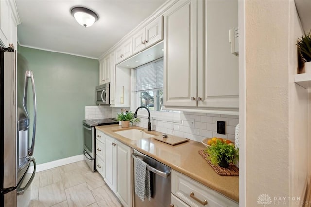 kitchen with decorative backsplash, appliances with stainless steel finishes, light countertops, white cabinetry, and a sink