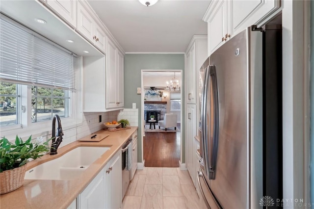 kitchen featuring tasteful backsplash, appliances with stainless steel finishes, light countertops, white cabinetry, and a sink