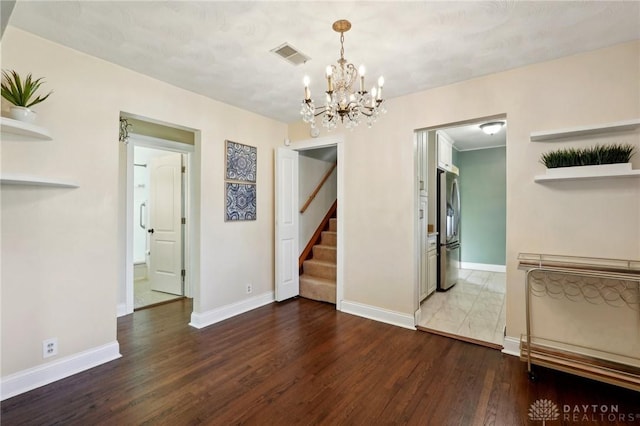 unfurnished room featuring visible vents, baseboards, and wood finished floors