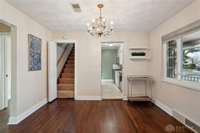 unfurnished dining area featuring dark wood-type flooring, visible vents, stairway, and baseboards