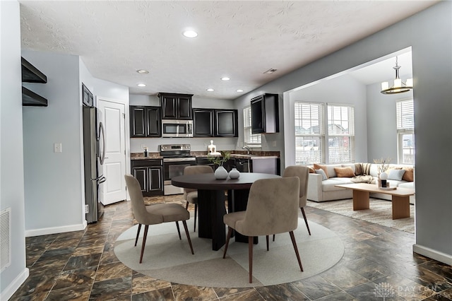 dining space featuring a textured ceiling, a chandelier, recessed lighting, baseboards, and stone finish floor