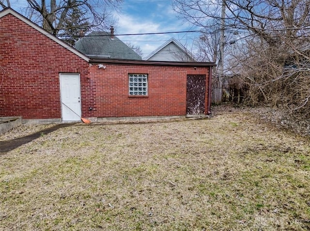 rear view of house featuring brick siding and a lawn