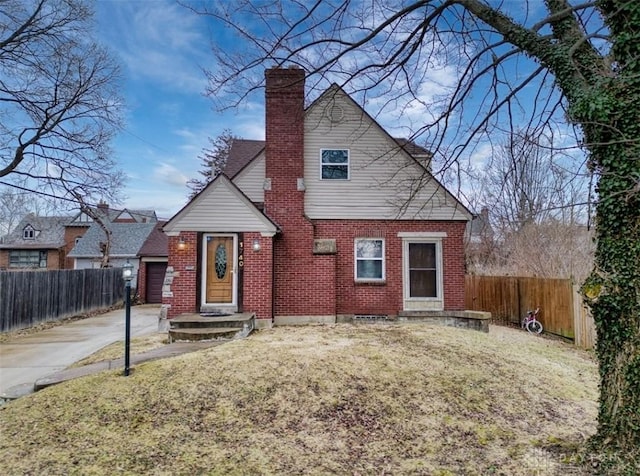 view of front of property featuring brick siding, a chimney, a front yard, and fence