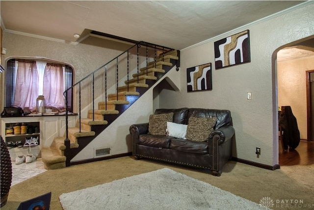 carpeted living area featuring a textured wall, arched walkways, and crown molding