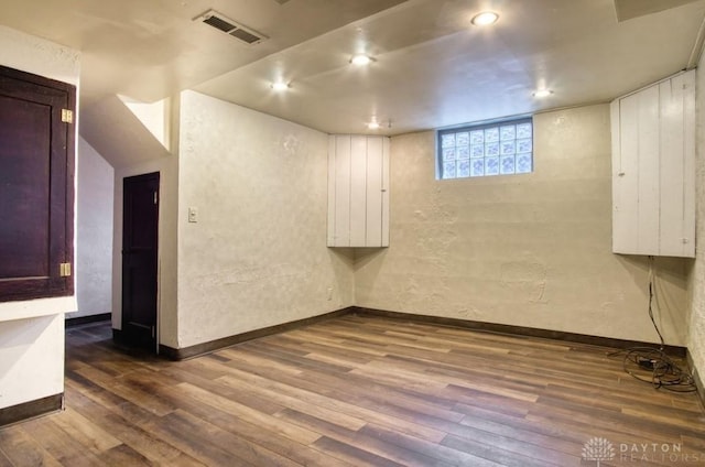 below grade area with dark wood-style floors, recessed lighting, visible vents, and baseboards