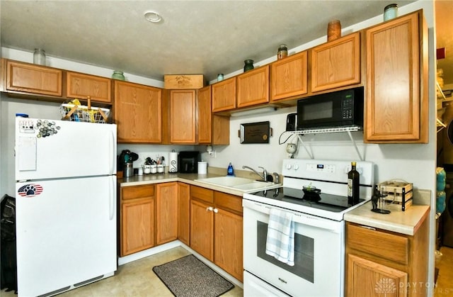 kitchen featuring light countertops, white appliances, a sink, and brown cabinets