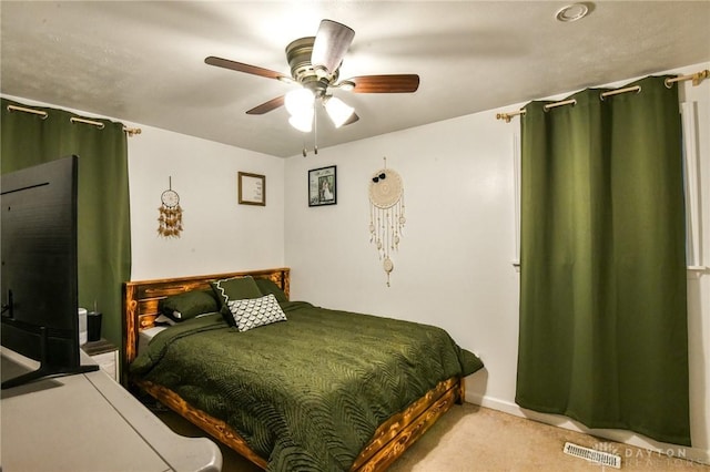 bedroom featuring visible vents, a ceiling fan, and light colored carpet