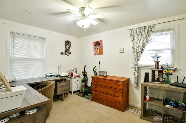 office space with light carpet, visible vents, and a ceiling fan