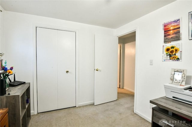 bedroom featuring baseboards, a closet, and light colored carpet