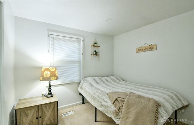 bedroom with baseboards, visible vents, and light colored carpet