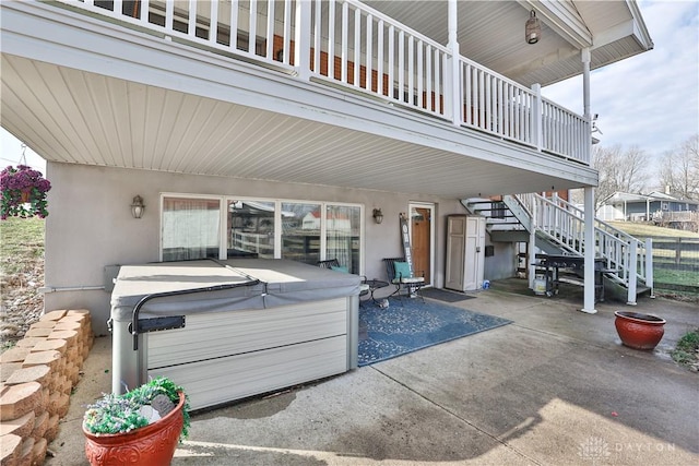 view of patio with fence, stairs, a balcony, and a hot tub