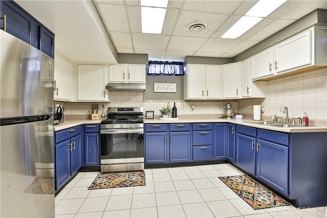 kitchen with a sink, a drop ceiling, stainless steel appliances, blue cabinetry, and under cabinet range hood