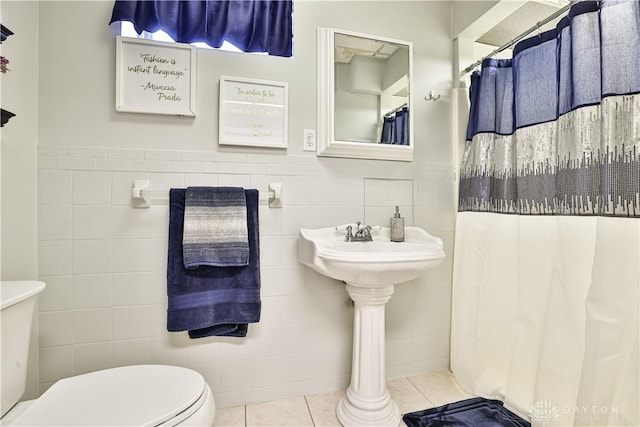 bathroom featuring tile patterned floors, tile walls, a wainscoted wall, toilet, and a shower with shower curtain