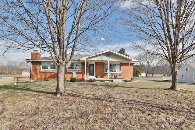 ranch-style house with a front lawn, covered porch, brick siding, and a chimney