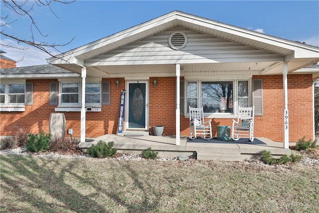 ranch-style home with a porch, brick siding, and a front yard