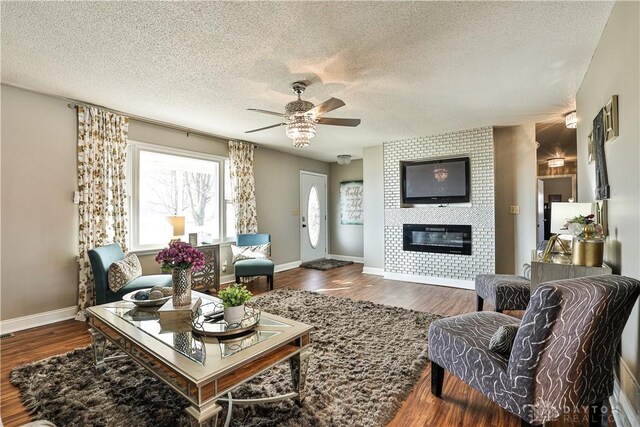 living area featuring dark wood-style floors, a textured ceiling, baseboards, ceiling fan, and a tile fireplace