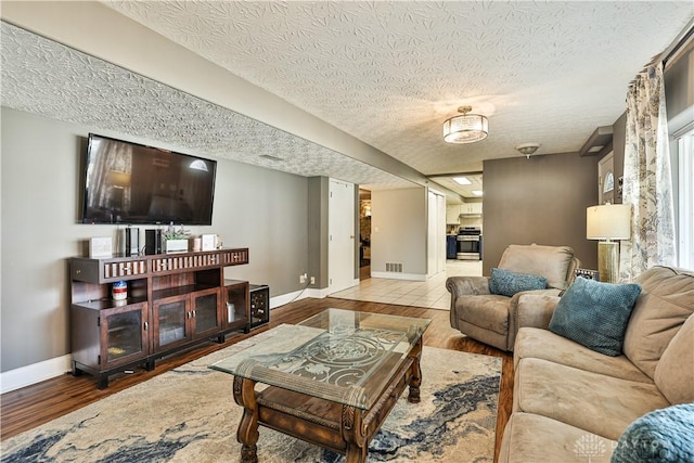living area with wood finished floors, baseboards, and a textured ceiling