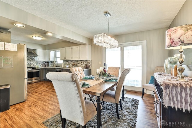 dining space with a chandelier, light wood-type flooring, and a textured ceiling