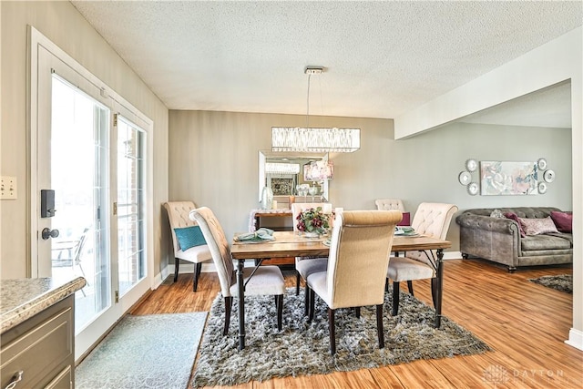 dining space featuring wood finished floors, a textured ceiling, and plenty of natural light
