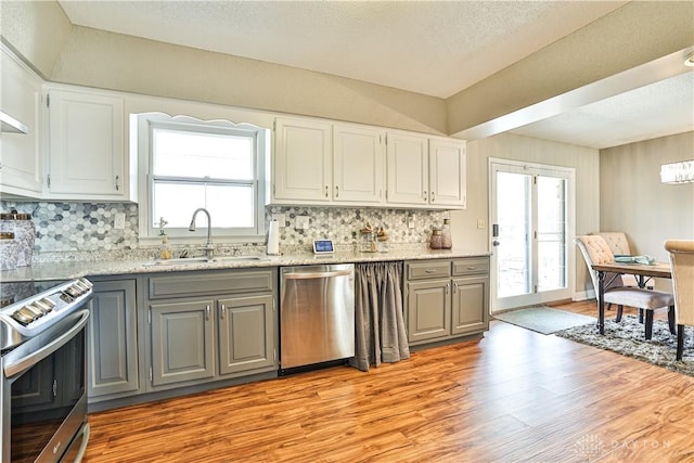 kitchen featuring gray cabinets, light wood-style flooring, stainless steel appliances, and a sink