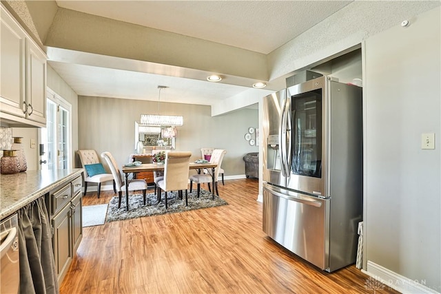kitchen with a chandelier, stainless steel fridge, pendant lighting, light wood finished floors, and baseboards
