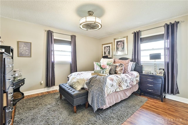 bedroom with baseboards, wood finished floors, and a textured ceiling